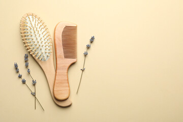 Hair brush, comb and lavender flowers on beige background, top view. Space for text