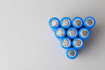 Many AA cell batteries on light grey background, top view. Space for text