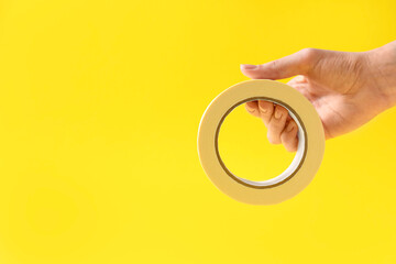 Woman holding masking tape on yellow background, closeup. Space for text