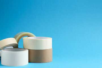 Rolls of different adhesive tapes on light blue background, space for text
