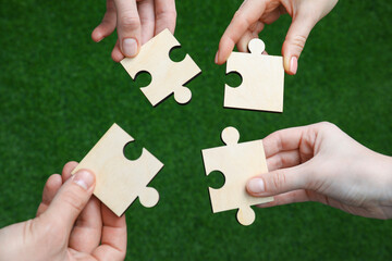 Teamwork. Group of people putting puzzle pieces together on blurred background, top view