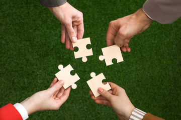 Teamwork. Group of people putting puzzle pieces together on blurred background, top view
