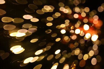 Blurred view of golden lights on dark background, bokeh effect