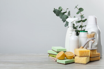 Eco-friendly cleaning products, supplies and eucalyptus branches on wooden table, space for text