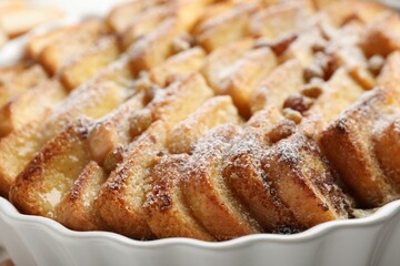 Delicious bread pudding with raisins and powdered sugar in dish, closeup