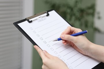 Woman filling Checklist with pen indoors, closeup