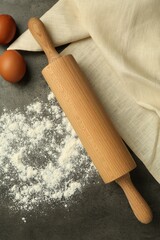 Rolling pin, flour and eggs on grey table, flat lay