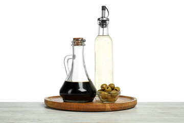 Vinegars in bottles and olives on wooden table against white background