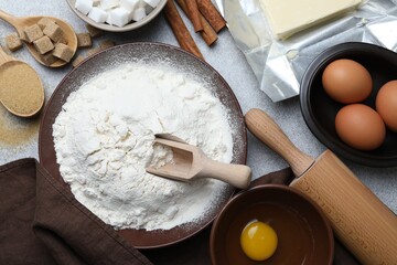 Rolling pin and ingredients for dough on light grey table, flat lay