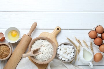 Rolling pin and ingredients for dough on white wooden table, flat lay. Space for text
