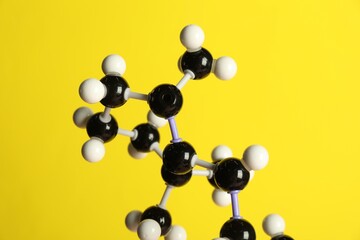 Molecule of retinol (vitamin A) on yellow background, closeup. Chemical model