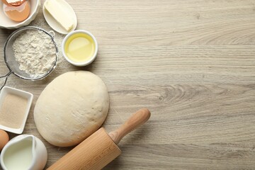 Rolling pin and different ingredients on light wooden table, flat lay. Space for text