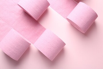 Color toilet paper rolls on light pink background, flat lay