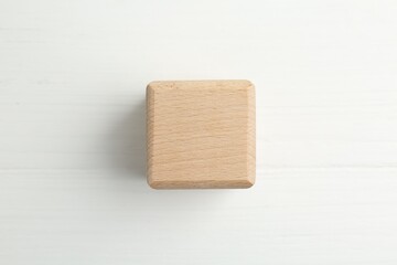 One wooden cube on white table, top view