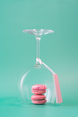 Pink French macarons in a wine glass minimal pastel festive arrangement on turquoise background