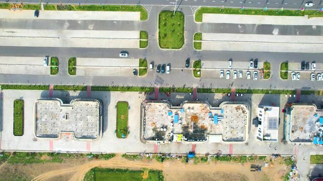 Aerial drone moving back straight down show showing midway rest area pitstop on the side of the busy delhi mumbai expressway with massive parking, green parks and multiple cars parked in front of the