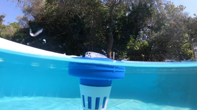 Split underwater view of chlorine dispenser in a swimming pool