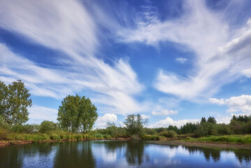 The landscape features a cloudy sky above a picturesque river.
