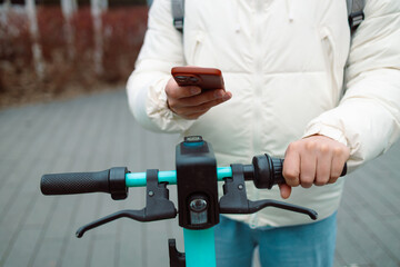 Handsome man using smartphone app. Guy approaches an electric scooter and using mobile phone app NFC contactless locker on bike bicycle in sharing parking lot. High quality photo