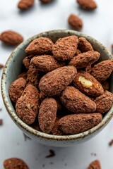 Bowl of coated almonds on a white marble table for a sweet treat or healthy snack