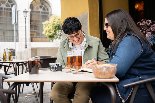 Lesbian couple enjoying a bar date with laughter and writing