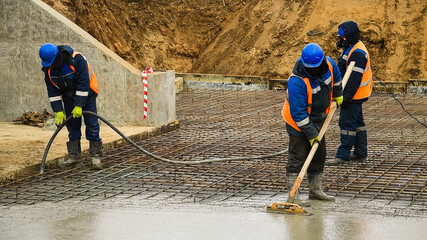 Workers are pouring structural concrete at a construction site