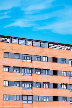 Modern orange brick apartment building under blue sky