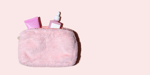 Pink cosmetic bag with skincare bottles on neutral background