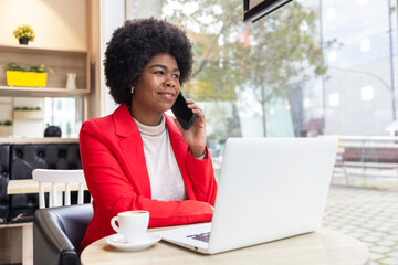 Confident woman in red blazer working in a cozy cafe setting