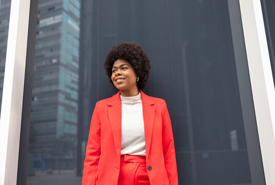 Woman in vibrant red suit exuding confidence in urban setting