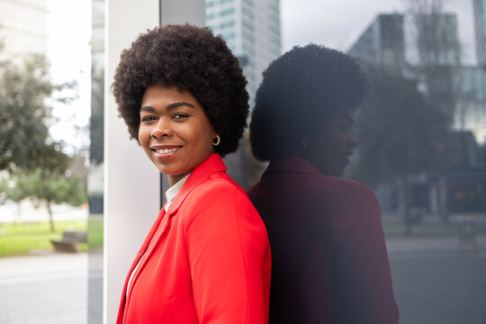 Confident woman in vibrant red jacket with urban backdrop