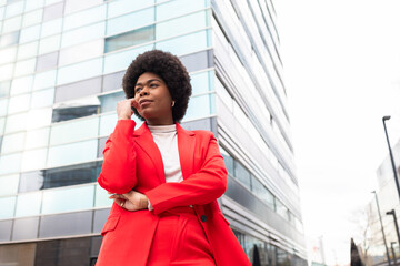 Confident Woman in Red Blazer Against Modern Urban Building