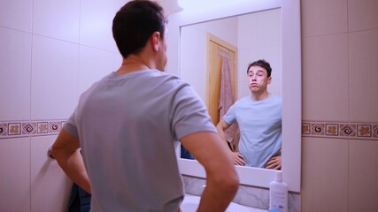 Sleepy man looking at mirror in bathroom before work