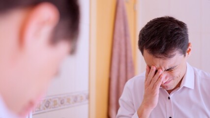 Businessman regretting mistake covering face in bathroom mirror