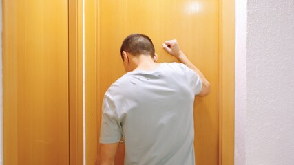 Impatient man knocking on bathroom door waiting to enter