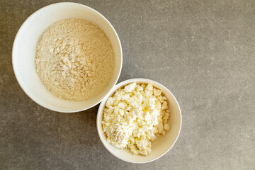 cottage cheese and flour in white bowls on kitchen counter