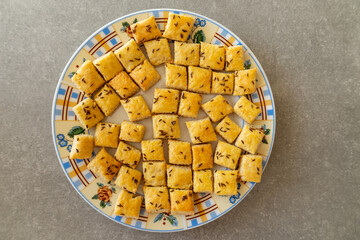 Homemade cottage cheese biscuits with caraway seeds in a patterned plate.