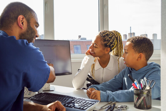 Male pediatrician discussing medical test results with mother and son in clinic