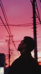 Man Contemplating a Vibrant Urban Sunset Silhouette with Power Lines Against Pink Sky Backdrop