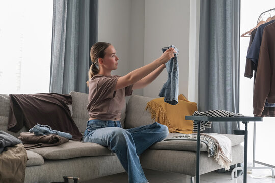 Spring cleaning,second hand,Fast fashion, the girl puts things in order in the closet. A bunch of colorful clothes. The concept of processing, second hand, eco, minimalism, consumption of goods