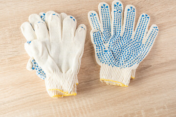 Two pairs of gloves, new worker cotton gloves on wooden background close-up.