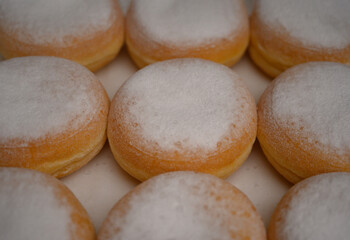 Close-up of golden donuts with sugar powder. Perfect texture and soft dough. Ideal for bakery promotions, coffee shop branding, and dessert advertising.