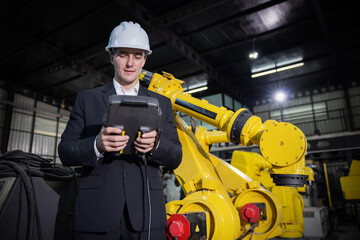 Caucasian engineer inspecting robotic arms in a manufacturing facility