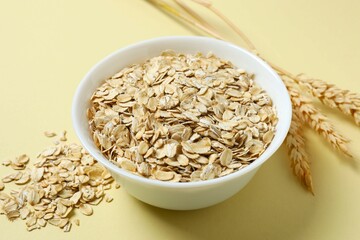 Composition with oatmeal flakes on beige background. Cooking breakfast
