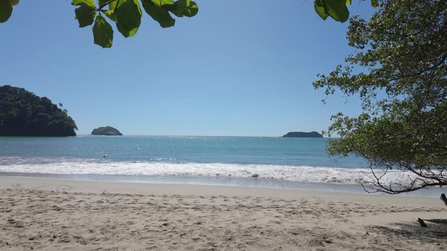 Golden sandy beach with crystal-clear turquoise ocean. Camera tracks forwards.