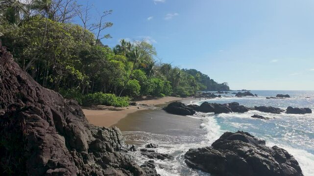 A rocky sandy deserted beach in Costa Rica, Bahia Drake, Drake's Bay - slow motion waves
