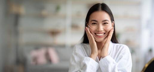In a peaceful environment, Asian woman expresses joy while receiving a facial massage, focusing on skin care and anti-aging benefits. The treatment offers relaxation and rejuvenation.
