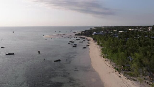 Panorama of sandy beach and nice ocean.background luxury resort and fishing boats moored.Summer travel in Zanzibar, Africa,Tanzania.