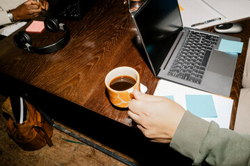 High angle view of male entrepreneur holding coffee cup near laptop on desk at office