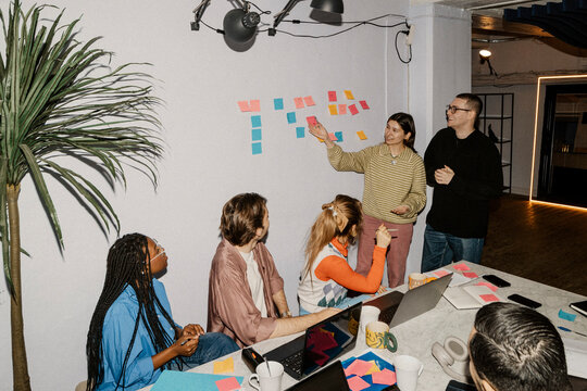 Female business professional communicating with colleagues during meeting at office